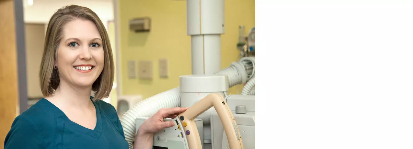 Smiling technician standing next to imaging equipment