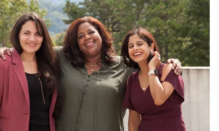 Three women standing and smiling outside